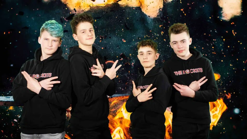 Vier junge Männer posieren vor einem Feuer und nehmen an einem Musikworkshop teil.